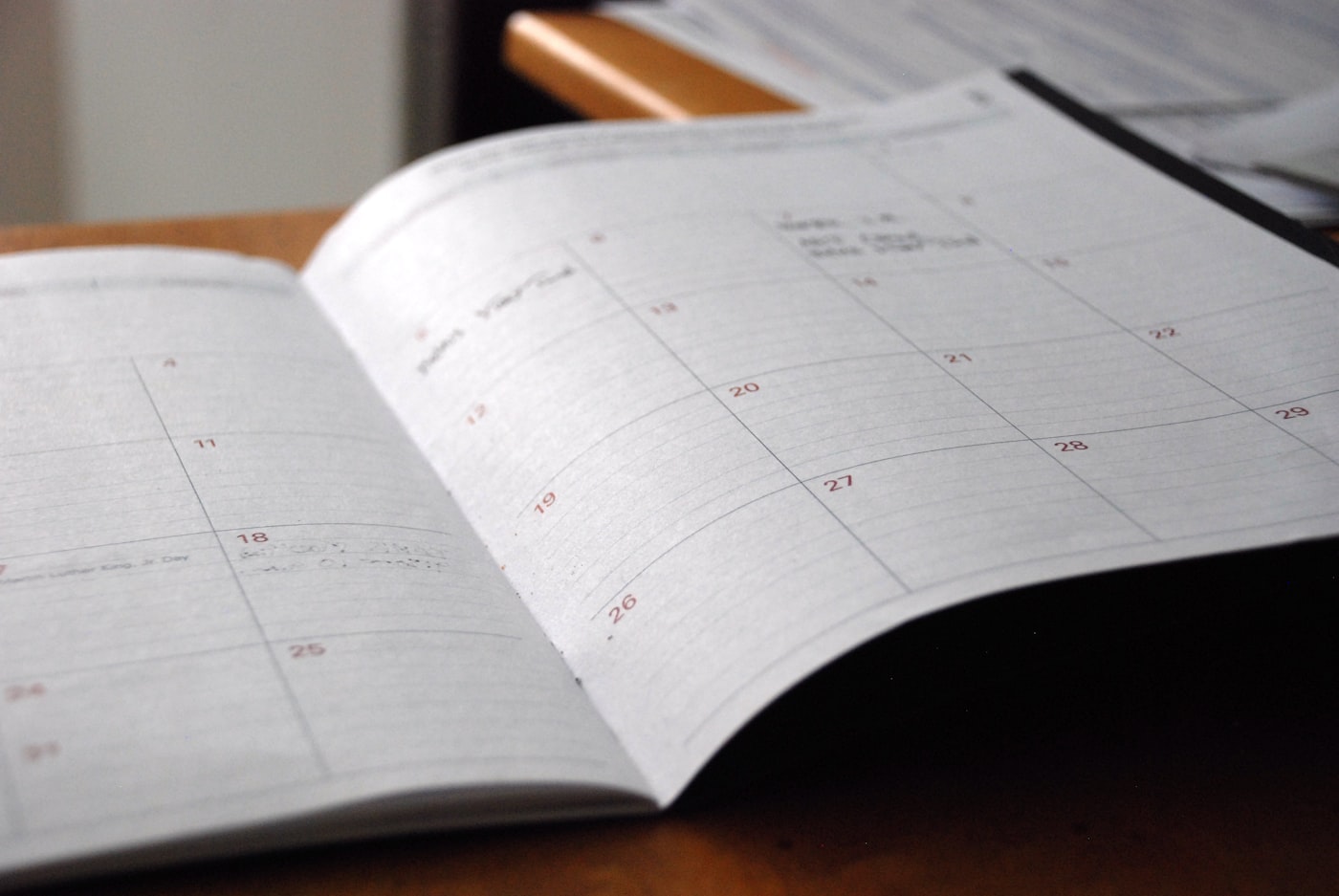 An open monthly planner lying on a wooden desk