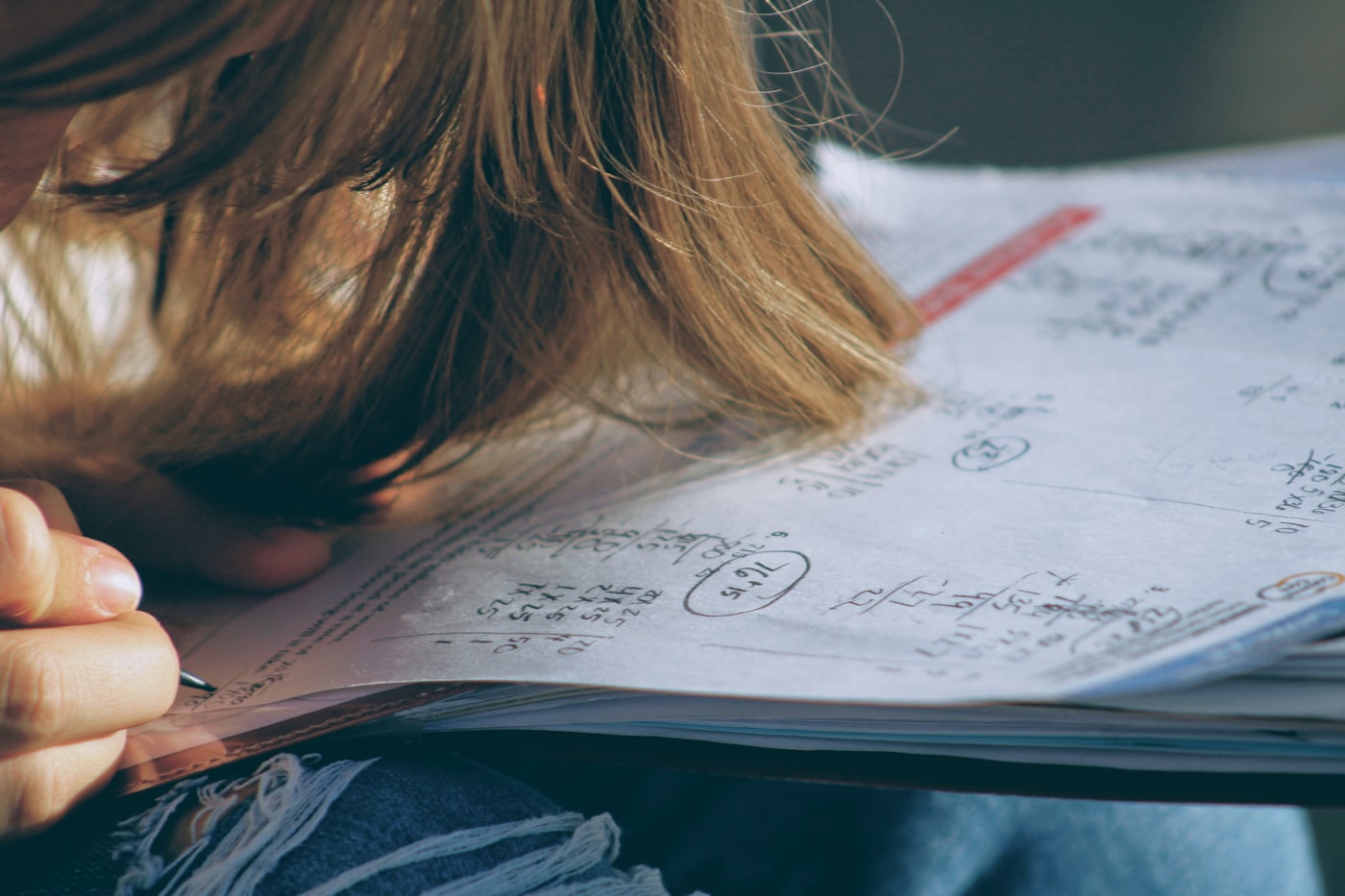 A primary-school student working through maths problems at a desk