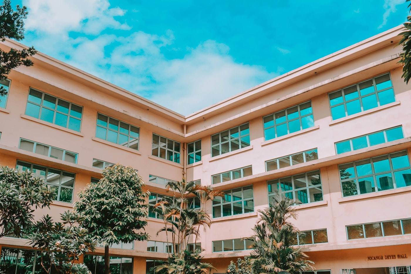 A modern public high school building with large windows and trees in front