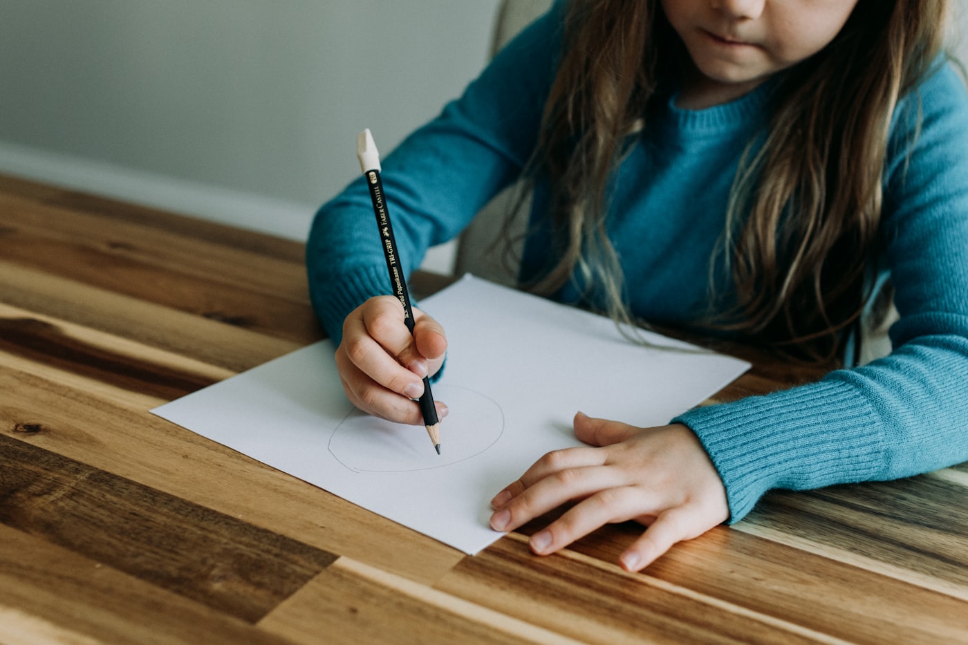 A child writing on a sheet of paper at a wooden table