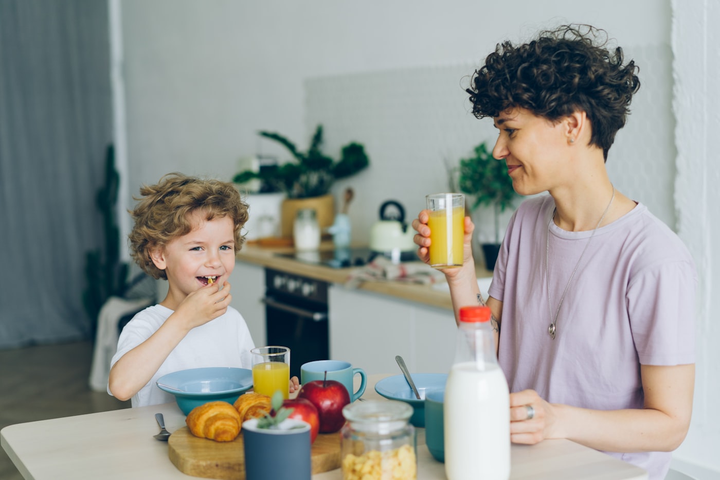 A parent and child sitting and talking at a kitchen table at home