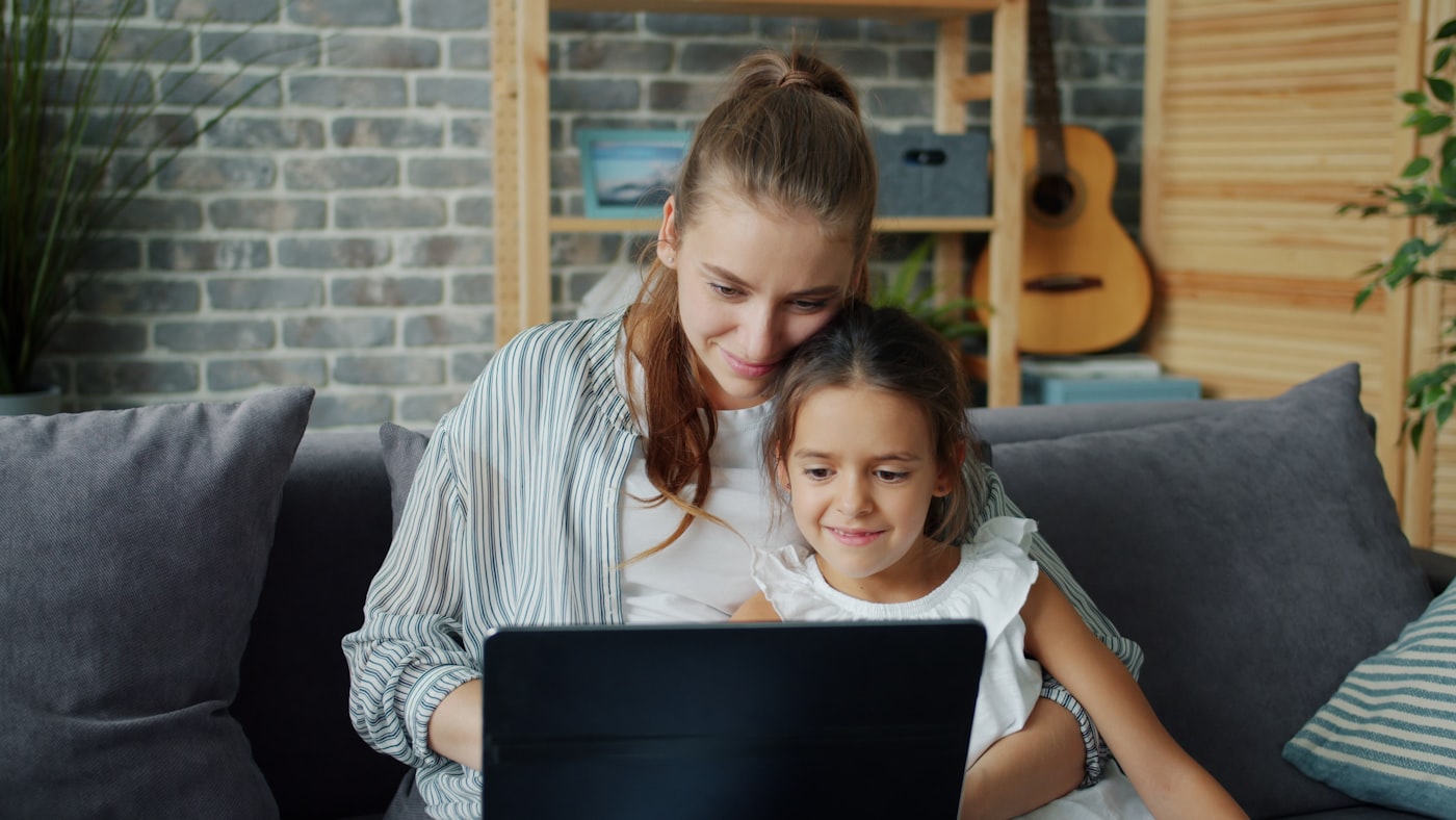 A parent and child looking at a laptop screen together at home